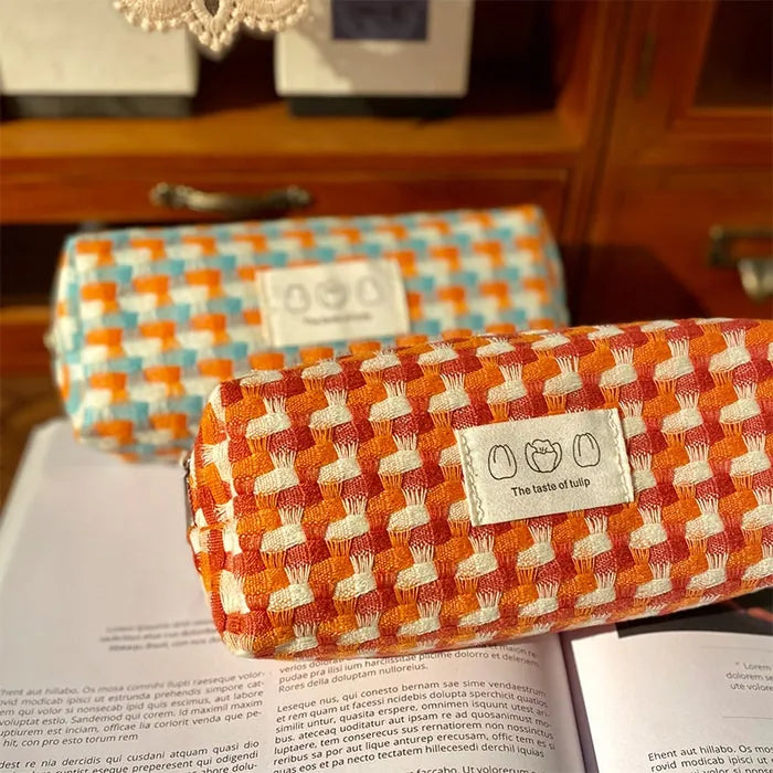 Dos estuches de punto en naranja y azul sobre un libro abierto